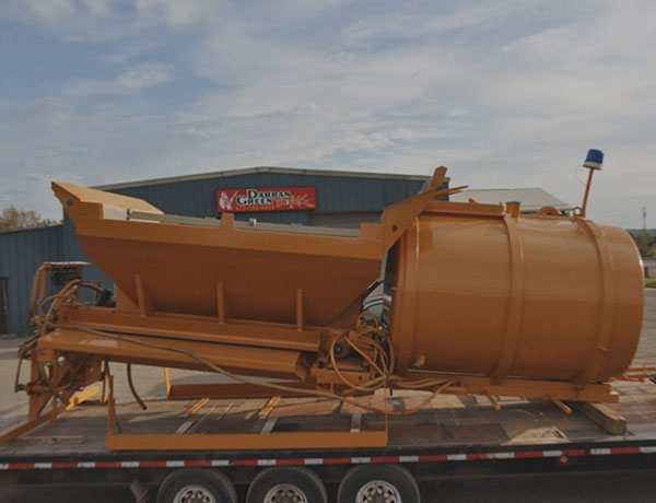 plural component equipment on a flatbed in front of shop