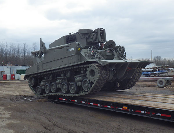 recently sandblasted and painted military equipment being loaded onto flatbed